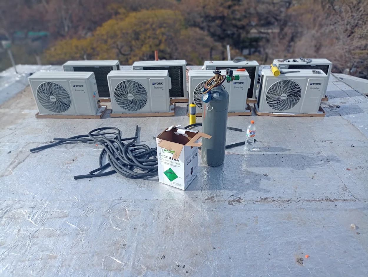 Cuatro unidades exteriores de aire acondicionado, herramientas, cilindro y materiales sobre una cubierta.