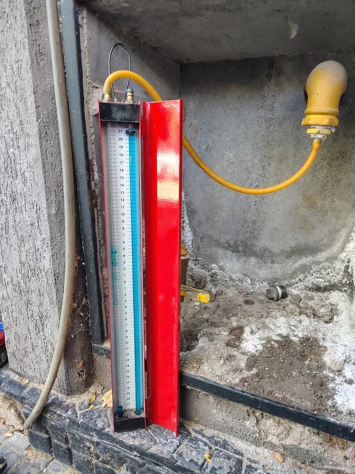 Manómetro de columna de agua conectado mediante una manguera amarilla a una instalación de gas.